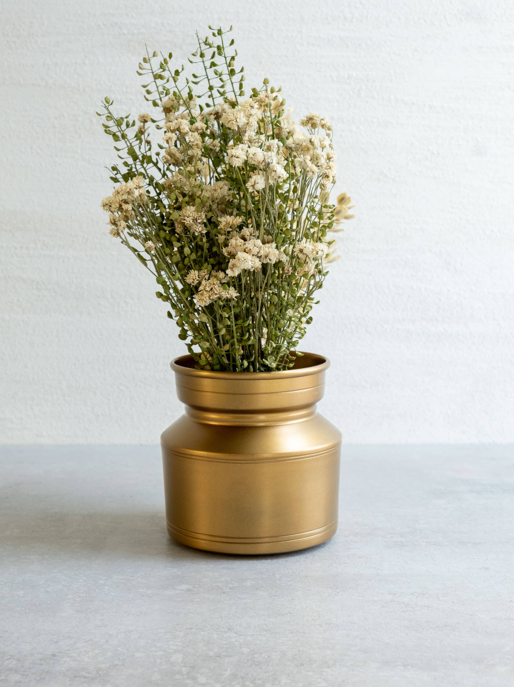 Gold vase with dried flowers on a light background